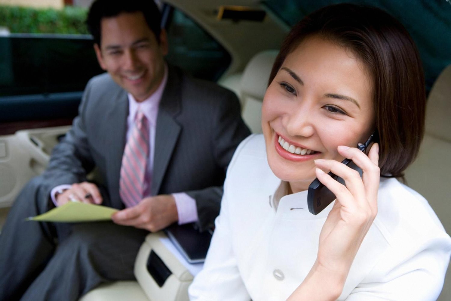 Corporate clients relaxing and taking calls in a chauffeured premium car in Dubai